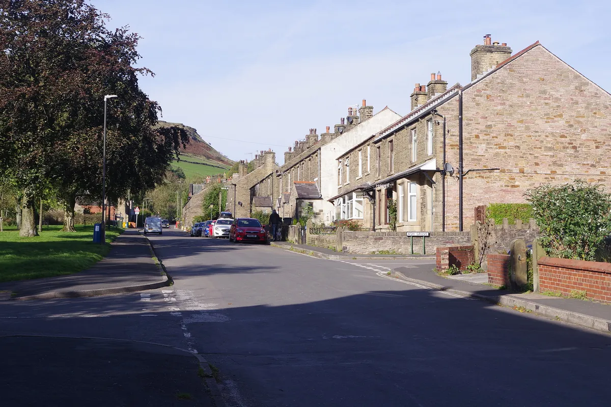 A row of stone terraced houses on Green Lane in Chinley, with hills behind