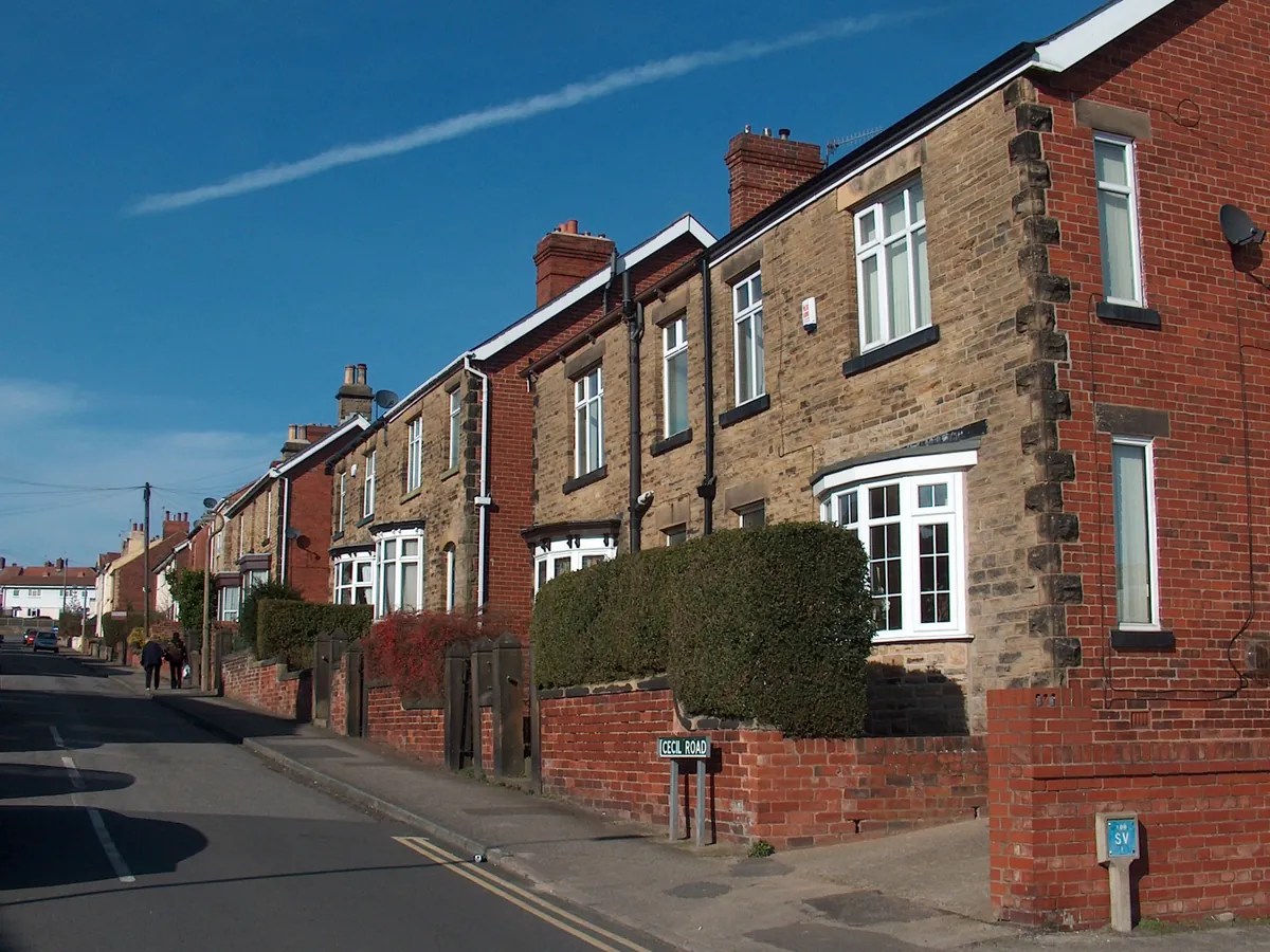 Stone and red-brick semi-detached houses with hedges on Cecil Road in Dronfield