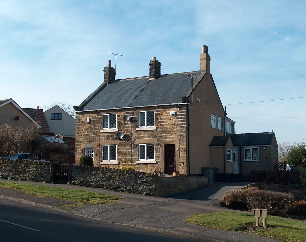 A pair of stone cottages behind a dry stone wall on Kiln Hill in Coal Aston